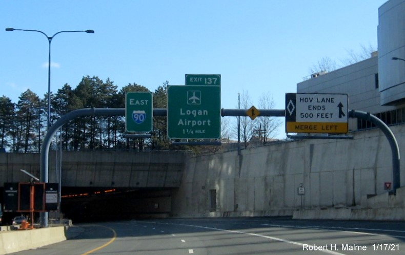 Image of 1-Mile advance overhead sign for Logan Airport exit with new milepost based exit number on I-90/Massachusetts Turnpike East in South Boston, January 2021