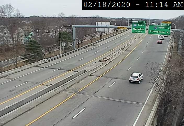 Traffic camera image of new exit numbers and yellow old exit number tabs on overhead signs for I-95 exits on RI 10 North in Providence