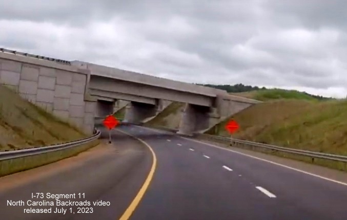 Image of US 74 West traffic going under new Business 74 ramp in future interchange with I-73/I-74 
       Rockingham Bypass, video from North Carolina Backroads, July 2023