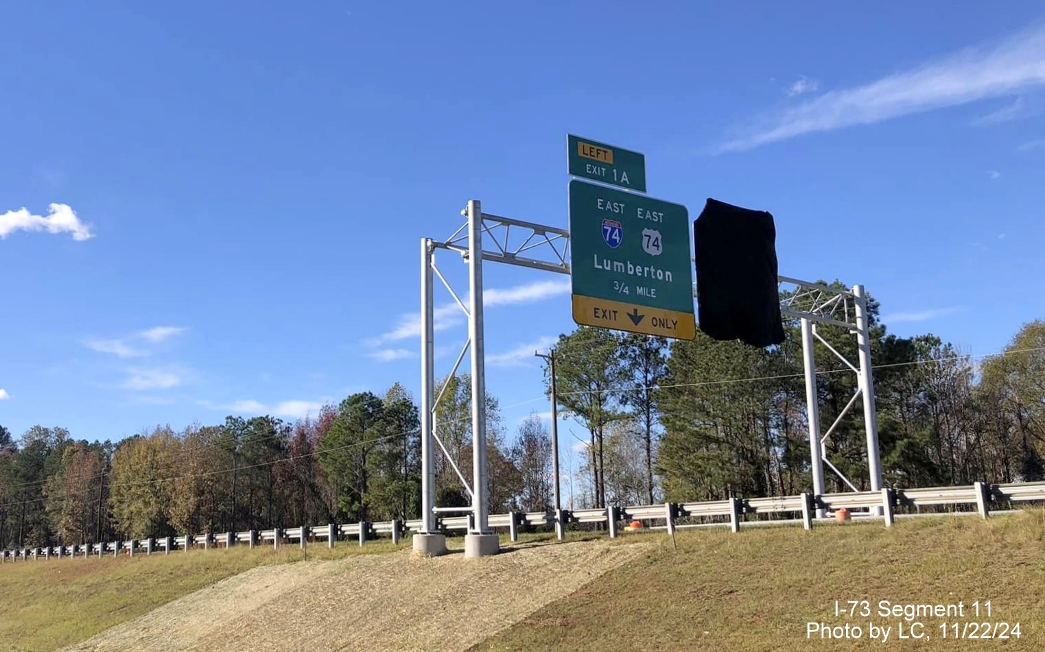 Image of recently placed overhead signage approaching exit ramp to US 74/Future I-74 East
        on Business US 74 West, by LC, November 2024