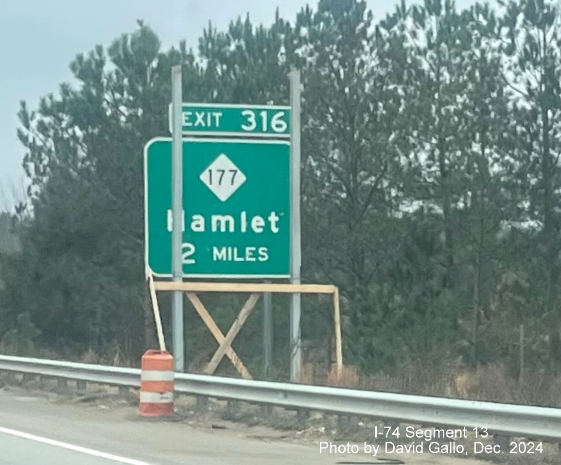 Image of new sign supports for NC 177 exit going up in front of old sign on US 74 (Future I-74) East 
        in Hamlet, by David Gallo, December 2024