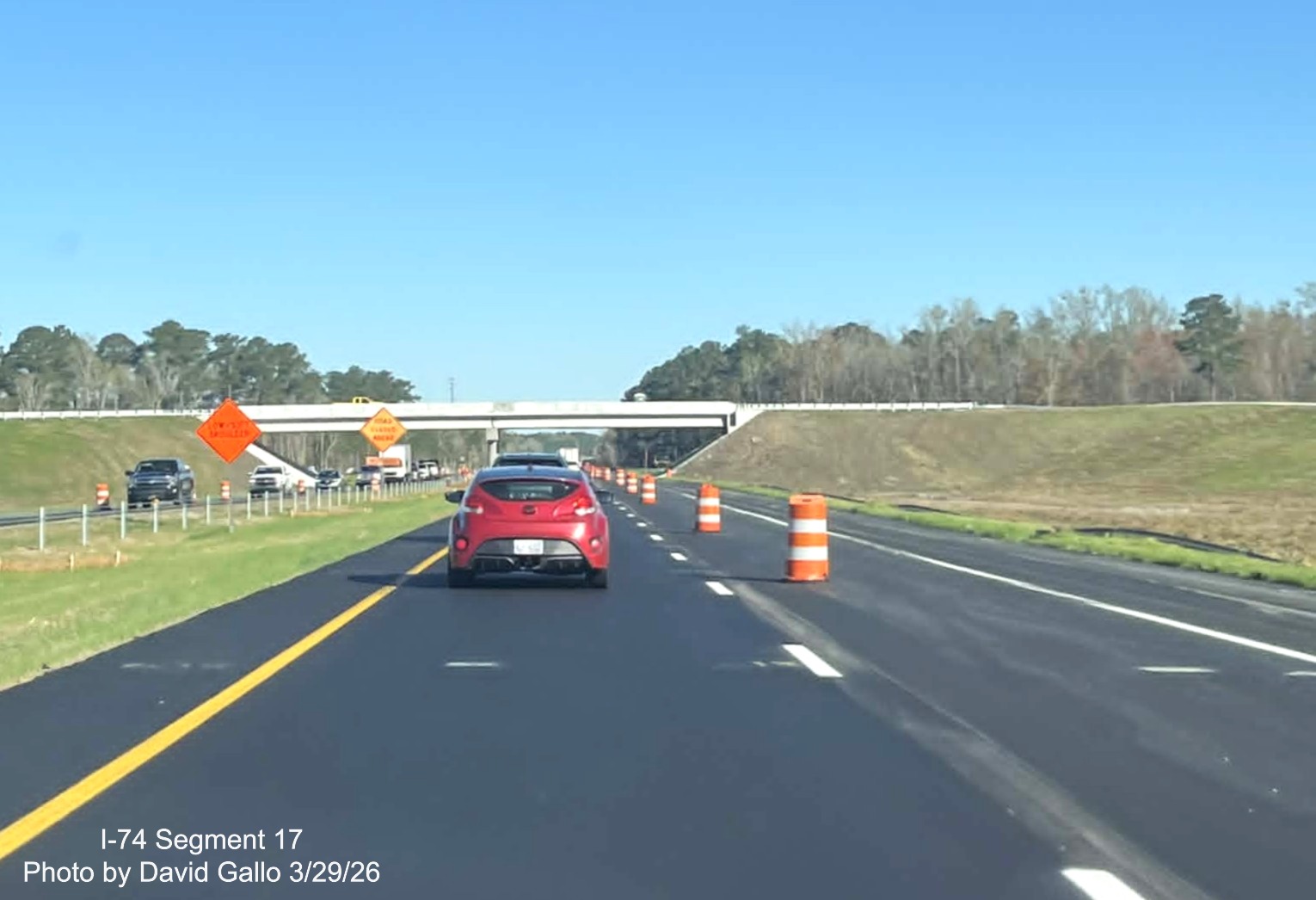 Image approaching the completed NC 72/ 130 West interchange bridge on US 74 
	  (Future I-74) East in Robeson County showing traffic barrels still in place, Google Maps Street View, February 2026