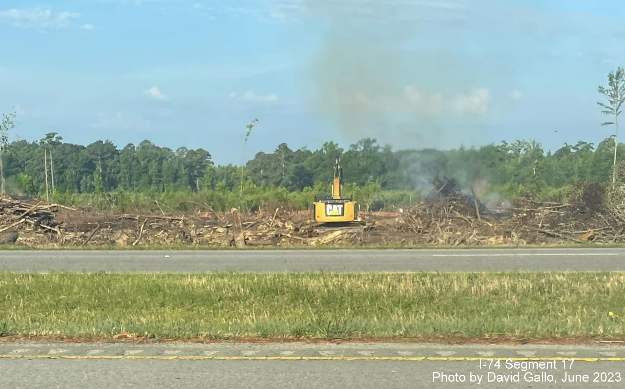 Image of brush being cleared and burned in area surrounding future interchange with US 74 
       (Future I-74) and NC 72/130, by David Gallo, June 2023