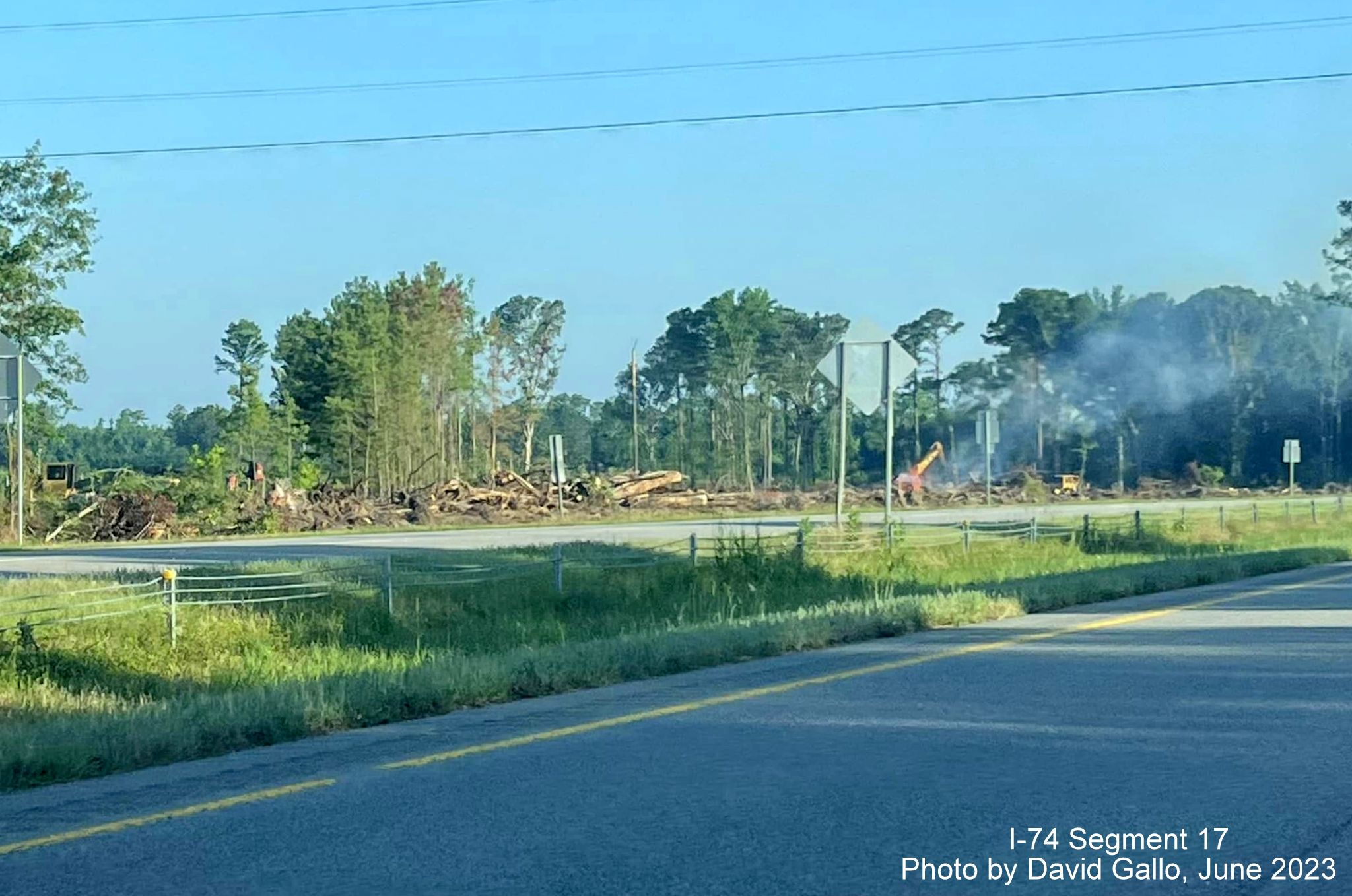 Image of brush being cleared and burned in area surrounding future interchange with US 74 
       (Future I-74) and NC 72/130, by David Gallo, June 2023