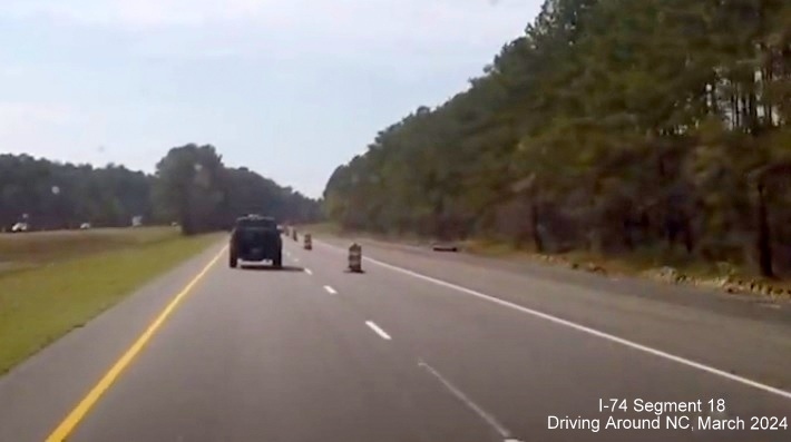 Image of end of interstate standard roadway on US 74/76 (Future I-74) West after future Lake Waccamaw 
        interchange, screen shot from video by Driving Around NC, April 2024