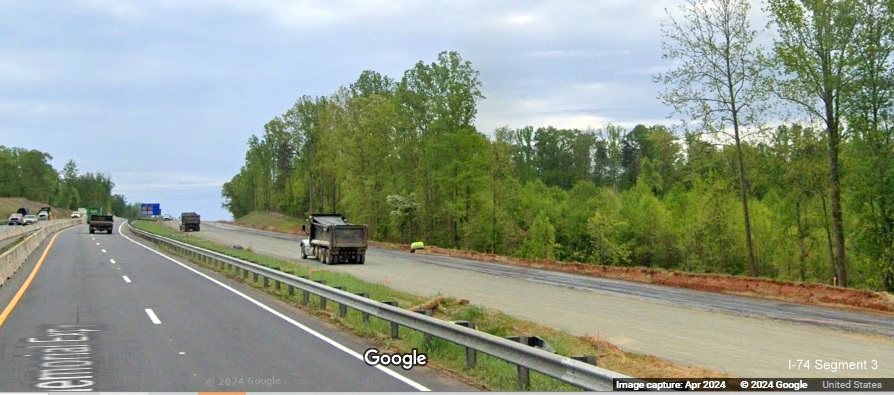 Image of construction trucks on future US 52 South (I-74 East) lanes prior to the NC 65 
        exit in the Beltway interchange construction zone, Google Maps Street View, April 2024