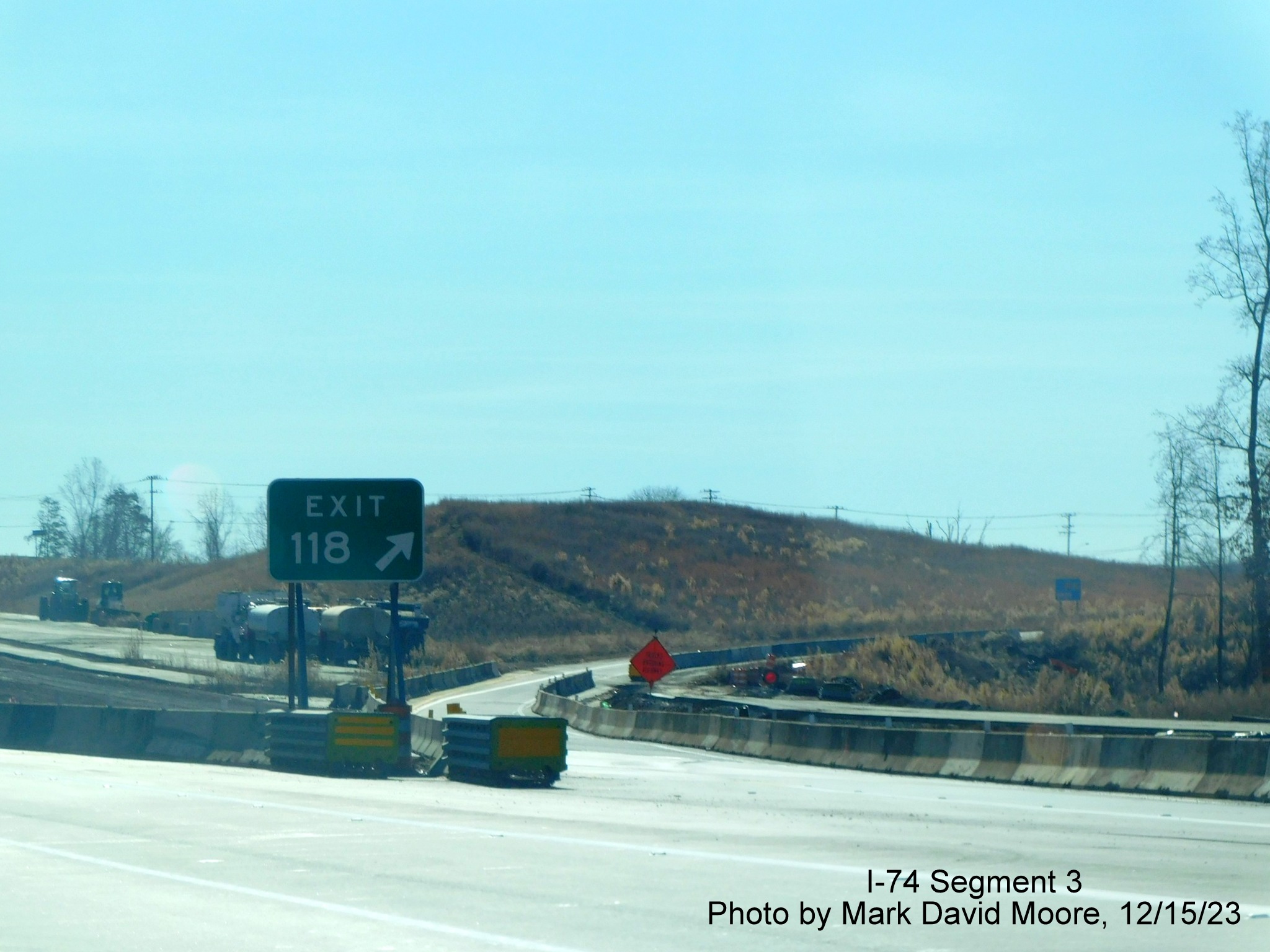 Image of gore sign for current NC 65 exit prior to completed Winston-Salem Northern Beltway 
        interchange, showing crossing of future eastbound lanes, by Mark David Moore, December 2023