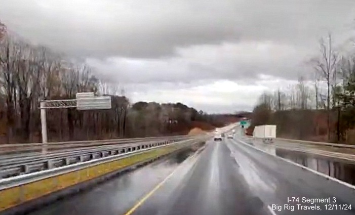 Image of newly placed overhead signs at ramp for Westinghouse Road exit on US 52 North 
       (Future I-74 West) in Rural Hall, seen heading south, screen grab from Big Rig Travels video, December 2024