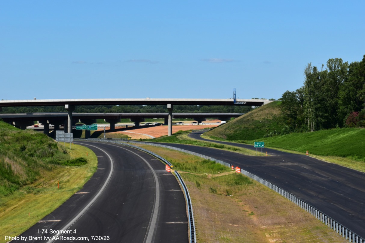 Image of I-74 roadway heading towards I-40 interchange with completed exit
	 signs, but incomplete flyover ramp, Brent Ivy at AARoads.com, July 30, 2026