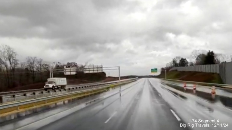 Image of newly placed overhead signage at ramp for NC 66/University Parkway exit on 
        completed 3 lane section of NC 74 (Future I-74) West/Winston-Salem Northern Beltway, screen grab from Big Rig Travels video, December         2024