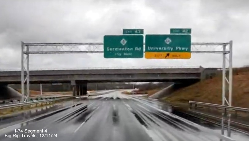 Image of newly placed overhead ramp sign for NC 66/University Parkway exit on 
        completed 3 lane section of NC 74 (Future I-74) East/Winston-Salem Northern Beltway, screen grab from Big Rig Travels video, December         2024