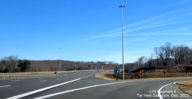 Image of temporary gore sign still in place for NC 66/University Parkway exit on NC 74 (Future I-74)
        East after segment from US 52 South opened, from video by Tar Heel Dashcam, December 2023