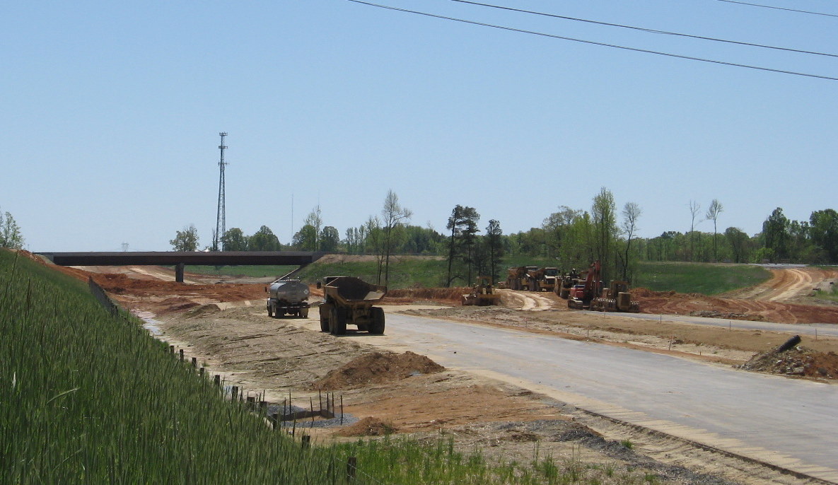 Photo of progress in moving dirt from under the Cedar Square Rd bridge to  
allow for grading of the I-74 freeway underneath, Apr 2010