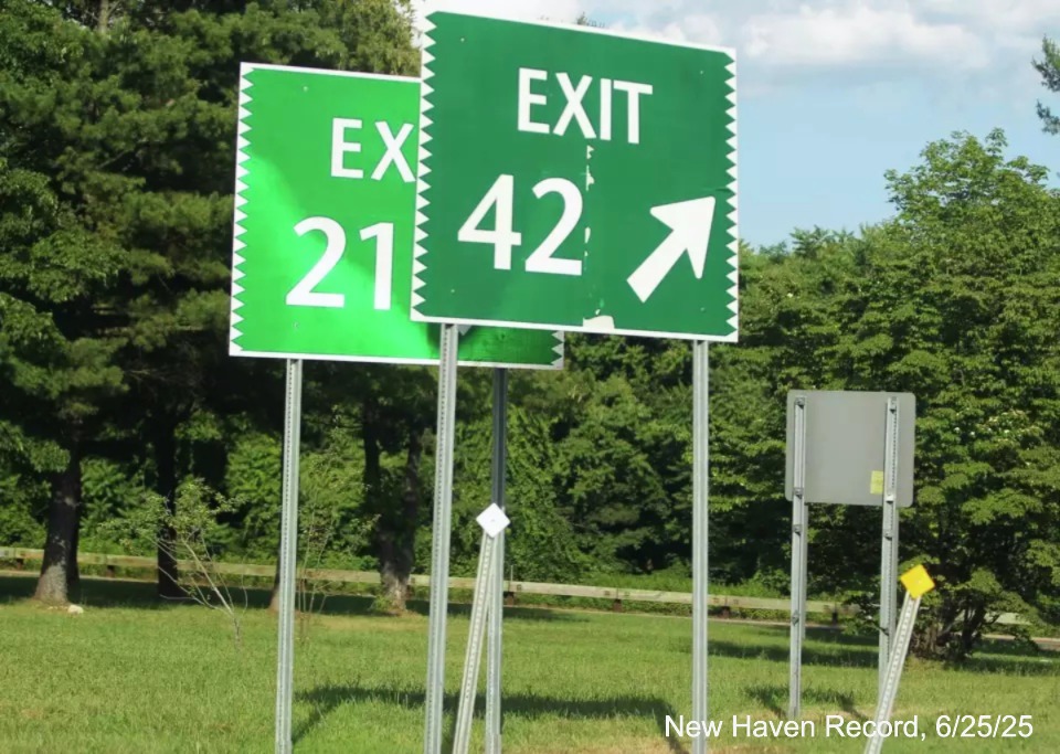 Image of existing gore sign for the CT 57 exit, with new 
 milepost based exit number version sitting behind it on CT 15 North/Merritt Parkway in Westport, New Haven Record, June 2025