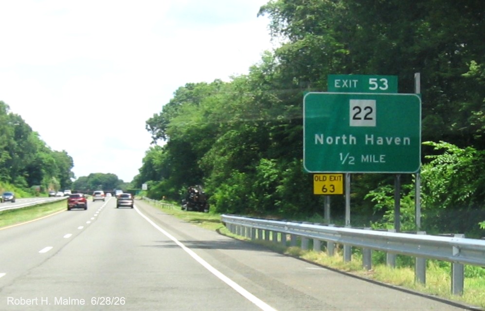 Image of ground mounted 1 Mile advance sign for the CT 22 exit, now with new milepost 
 based exit number and a yellow Old Exit 63 sign on support post and posts for future sign behind it on CT 15 North/Cross Parkway 
 in North Haven, June 2026