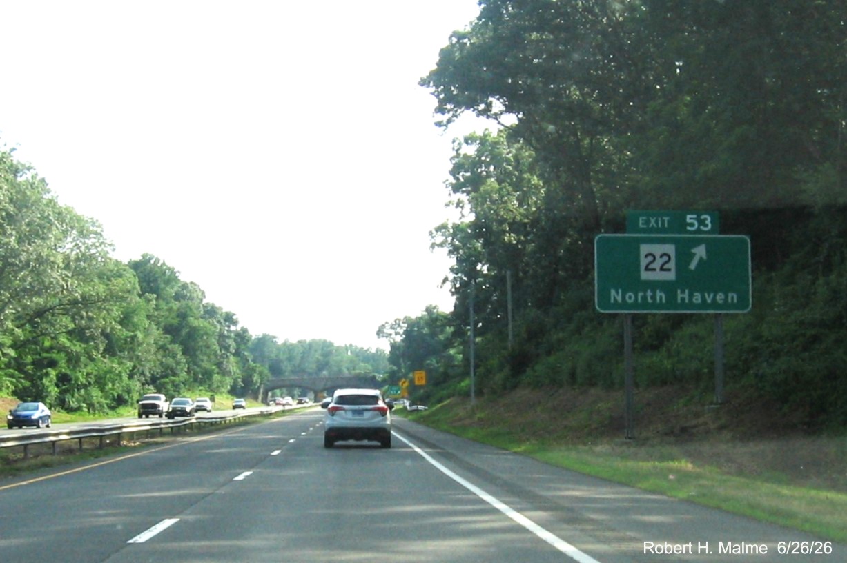 Image of new ground mounted ramp sign for the CT 22 exit, now with new milepost based exit 
 number and a yellow Old Exit 63 sign on support post on CT 15 South/Cross Parkway in North Haven, June 2026