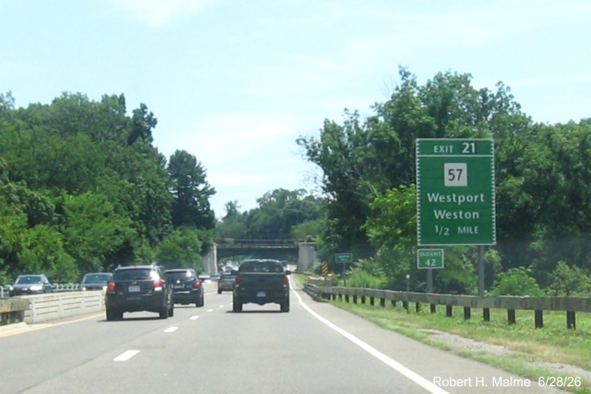 Image of the ground mounted 1/2 mile advance sign for the CT 57 exit, with new 
 milepost based exit number and Old Exit 42 tab on sign support on CT 15 North/Merritt Parkway in Westport, June 2026