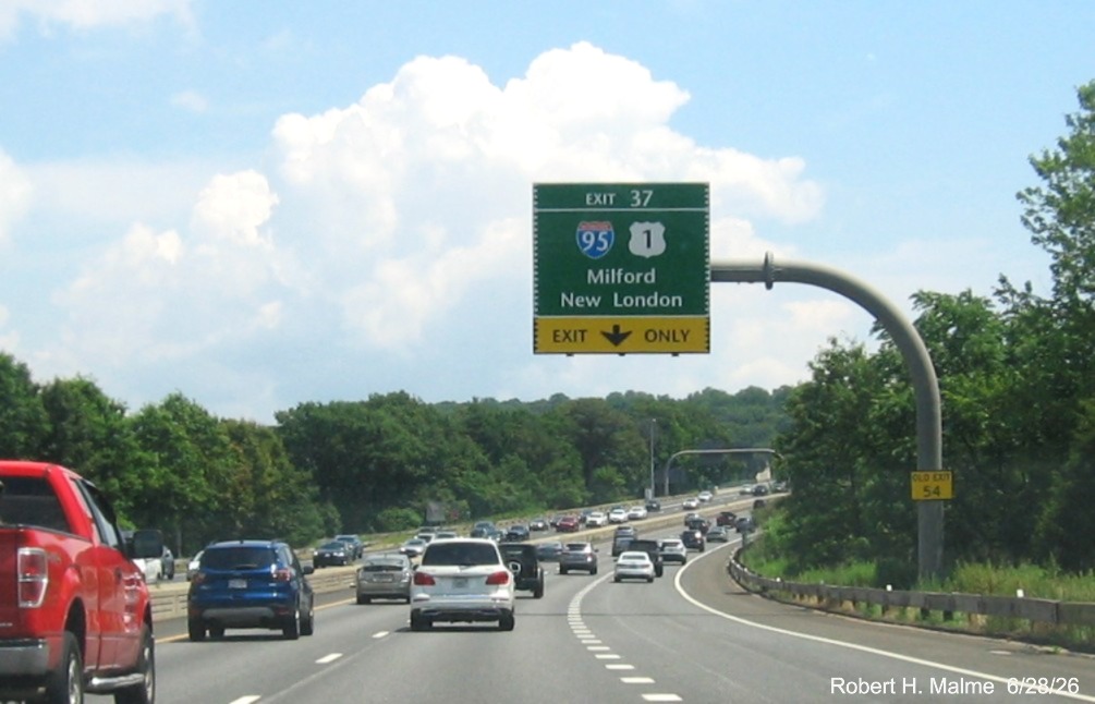 Image of 1 mile advance overhead sign for the (To) I-95/US 1 exit, with new milepost 
 based exit number and Old Exit 54 sign on support post on CT 15 North/Merritt Parkway in Stratford, by Jay Hogan, October 2025