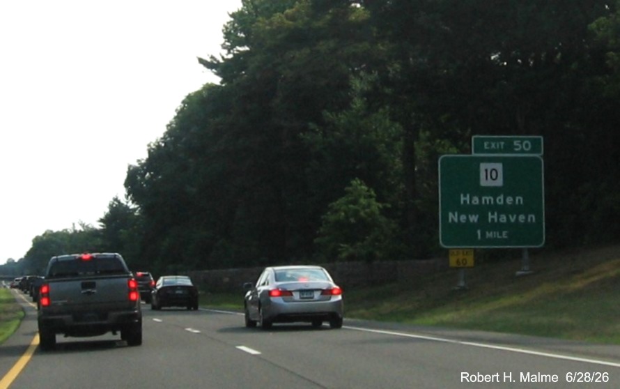 Image of new 1 mile advance ground mounted sign for the CT 10 exit, with new milepost based exit 
 number and yellow Old Exit 60 sign on support post on CT 15 South/Cross Parkway in Hamden, June 2026