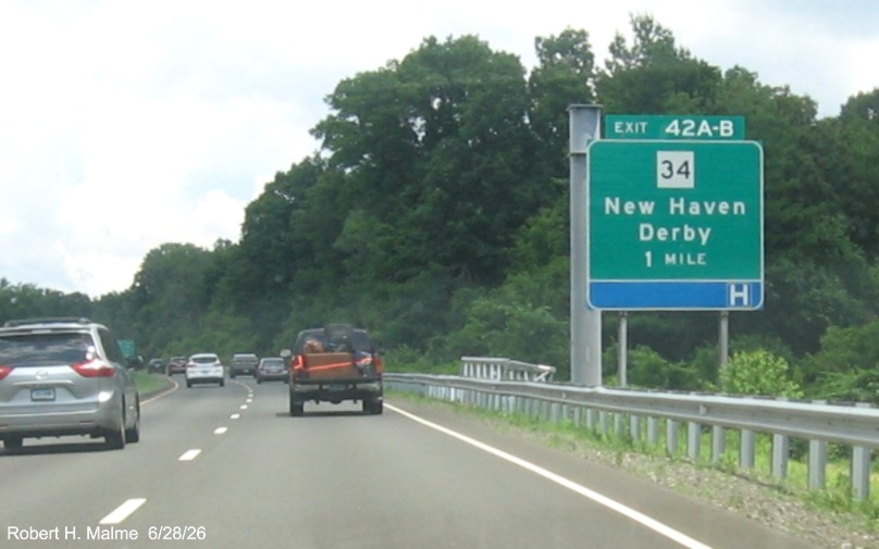 Image of ground mounted 1 Mile advance sign for the CT 34 exits, with new milepost 
 based exit numbers on CT 15 North/Cross Parkway in Derby and support for future overhead sign behind, June 2026