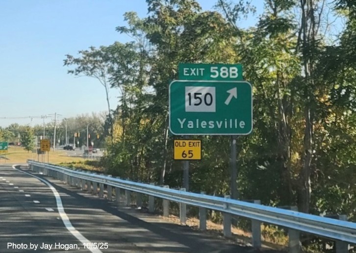 Image of ground mounted exit sign for the CT 150 exit, with
 new milepost based exit number overlays on exit tab and yellow Old Exit 65 sign on support post on CT 15 North/Cross Parkway 
 in Wallingford, by Jay Hogan, August 2025