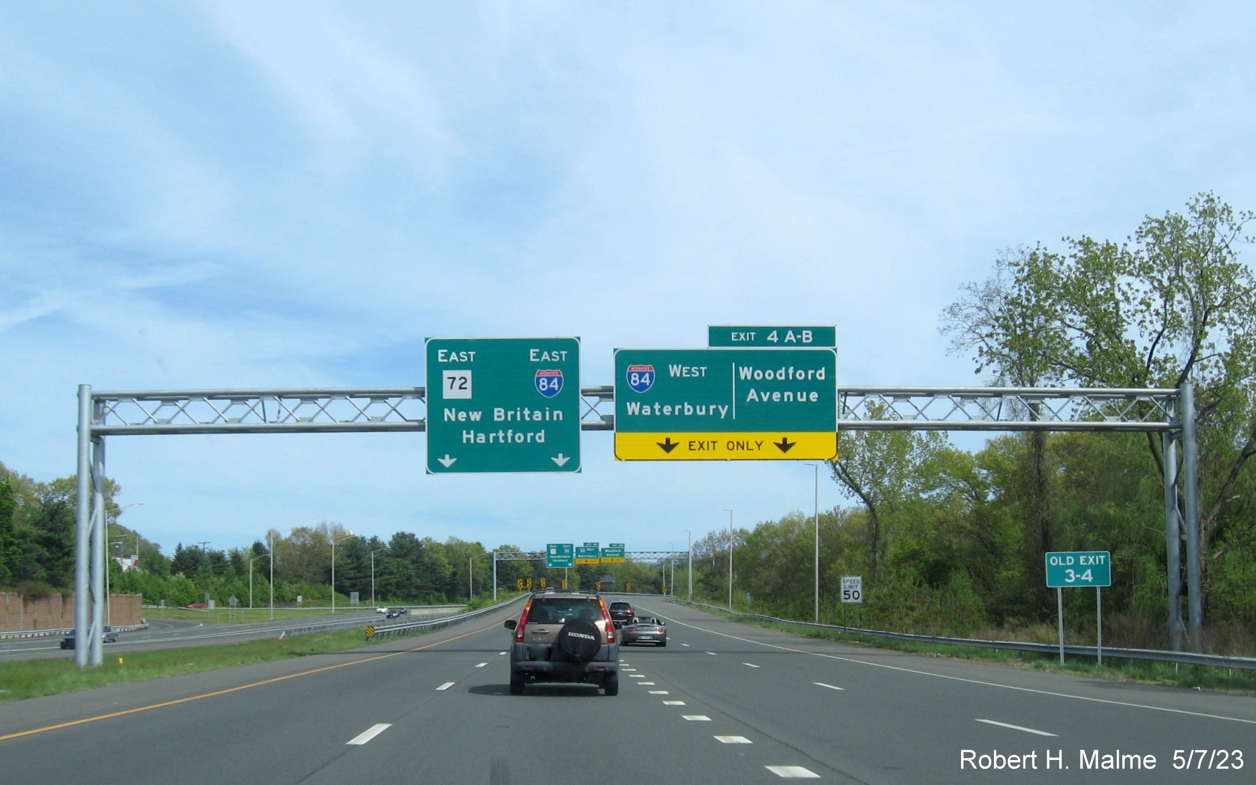 Image of 1/4 mile advance overhead sign for I-84 West/Woodford Avenue exits with new milepost based exit number and Old Exit 3-4 sign below on CT 72 East in Bristol, May 2023