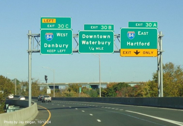 Image of overhead signage for I-84 and Downtown Waterbury exits with new milepost based 
        exit numbers on CT 8 North in Waterbury, by Jay Hogan, October 2024