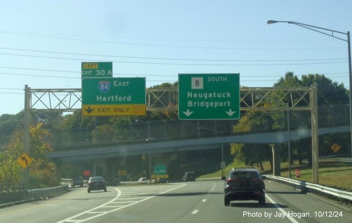 Image of overhead ramp sign for I-84 East exit with new milepost based 
        exit numbers on CT 8 South in Waterbury, by Jay Hogan, October 2024