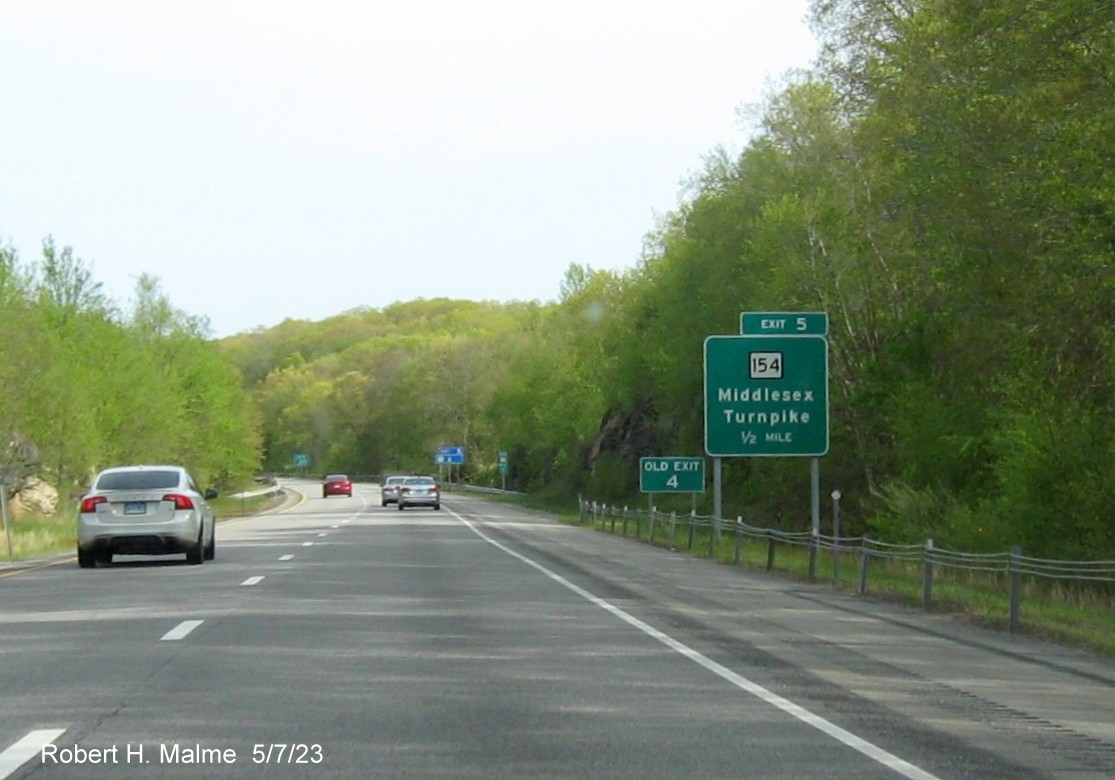 Image of 1 mile advance overhead sign for CT 154 exit with new milepost based exit number and separate Old Exit 4 in front on CT 9 South in Essex, May 2023