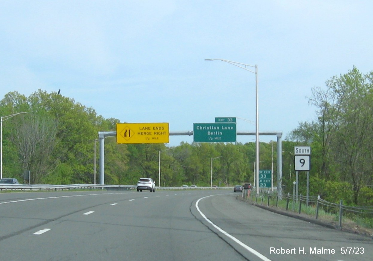 Image of 1/2 Mile advance overhead sign for Christian Lane exit with new milepost based exit number and New Exit/Old Exit 23 
      sign ground mounted in front on CT 9 South in Berlin, May 2023