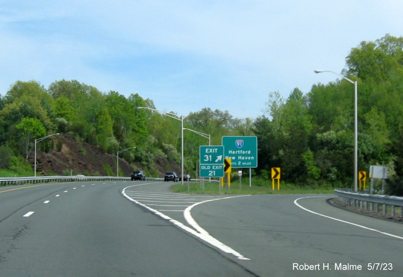 Image of gore sign US 5/CT 15 exit with new milepost based 
        exit numbers and Old Exit 21sign below on CT 9 South in Berlin, May 2023