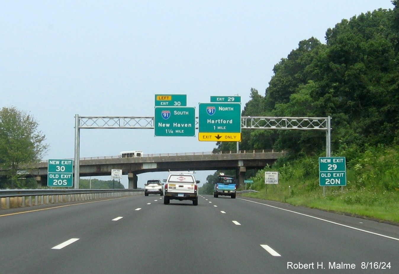 Image of 1 1/4 and 1 Mile advance overhead signs for I-91 exits with new milepost based exit number and 
      separate New and Old Exit signs in front on CT 9 North in Cromwell, August 2024