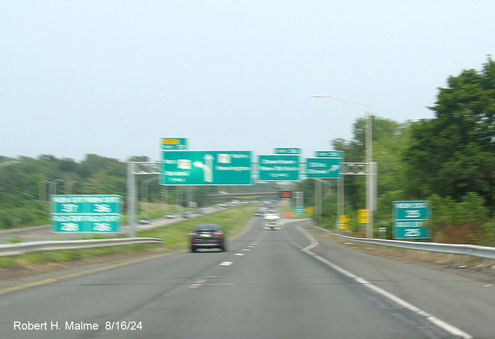 Image of overhead advance signs for CT 72 West and Downtown New Britain exits at ramp for Ellis Street 
      exit with new milepost based exit number and three sets of separate New and Old Exit signs in front on CT 9 North in New Britain, August 2024