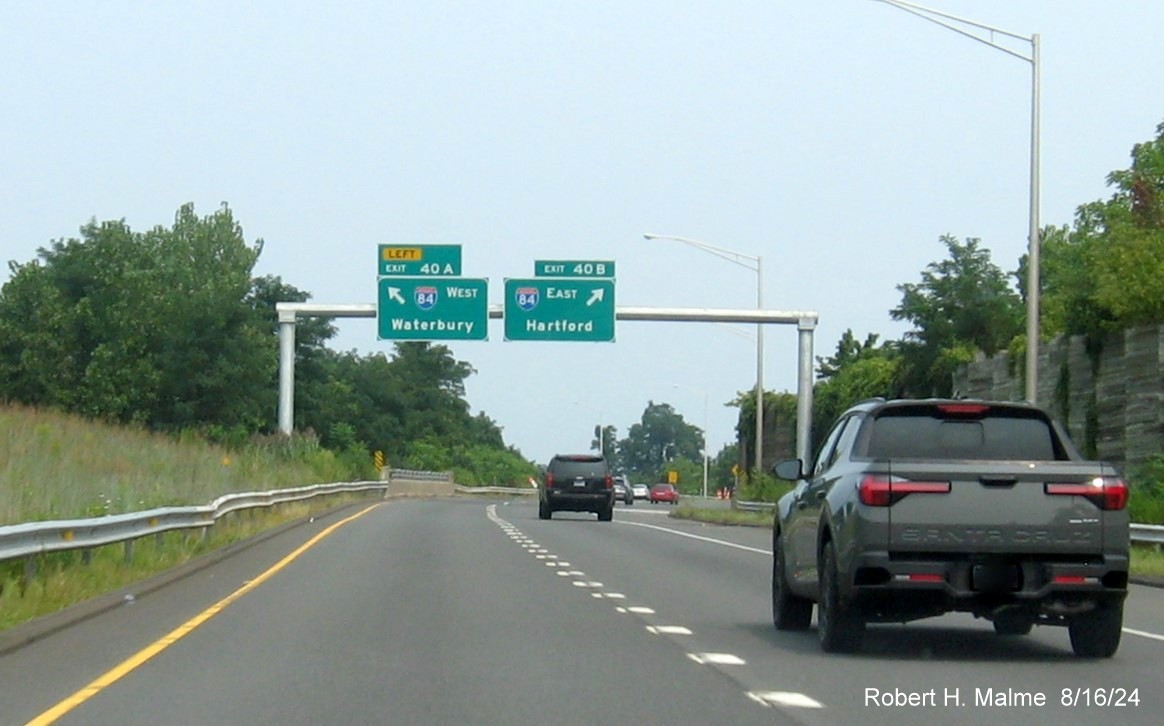 Image of advance overhead signs for I-84 ramps with new milepost based exit number and 
      separate Old Exit sign in front on CT 9 North in Farmington, August 2024