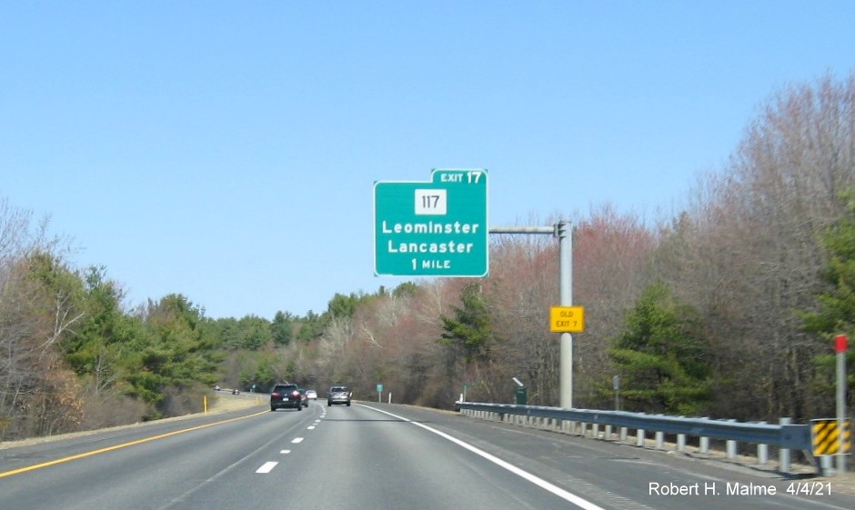 Image of 1 Mile advance overhead sign for MA 117 exit with new milepost based exit number and yellow Old Exit 7 sign on support on I-190 North in Leominster, April 2021