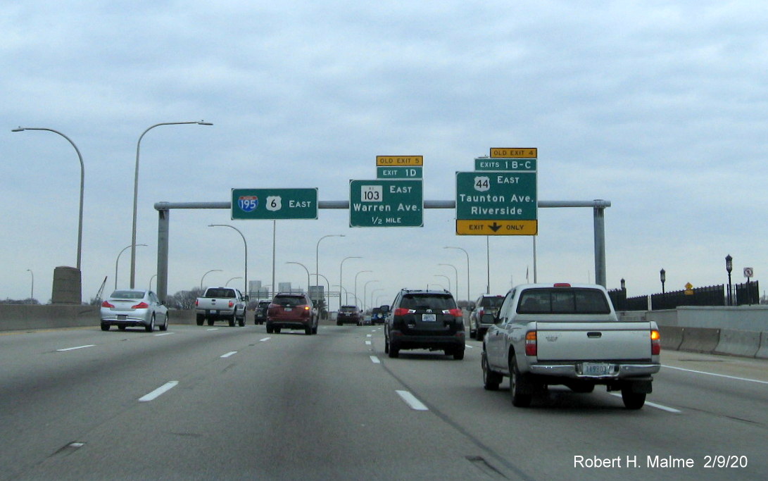 Image of overhead advance signs for US 44 and RI 103 exits with new milepost based exit numbers and yellow old exit tabs on I-195 East in East Providence