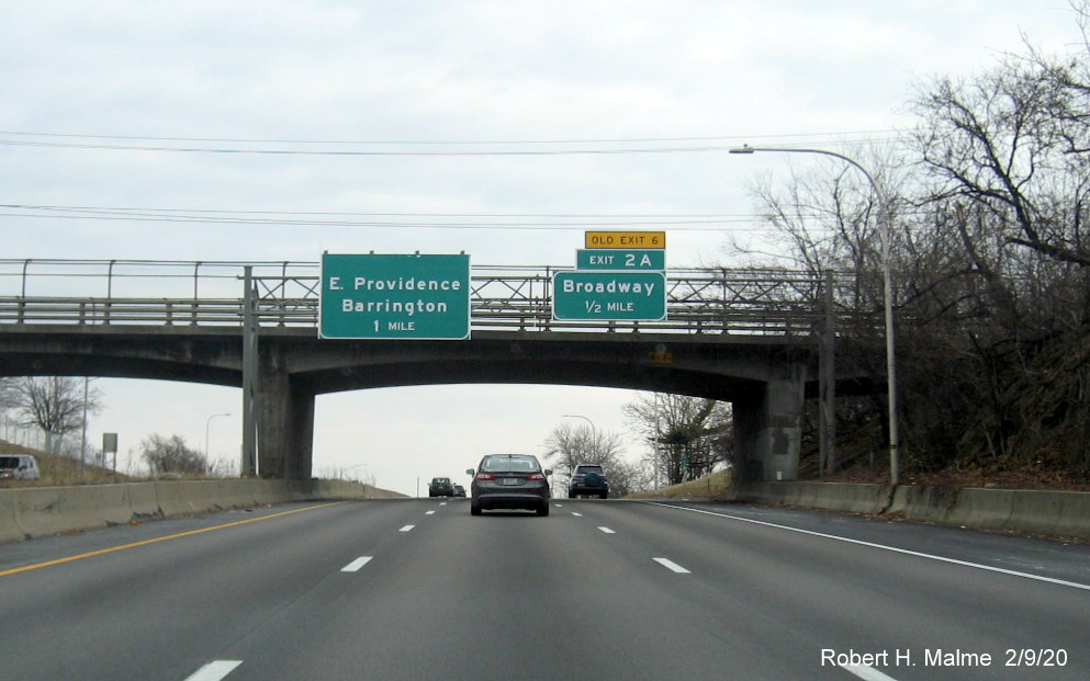 Image of overhead advance signs, one incomplete, with new milepost based exit numbers and yellow old exit tabs for RI 114 and Pawtucket Avenue exits on I-195 East in East Providence