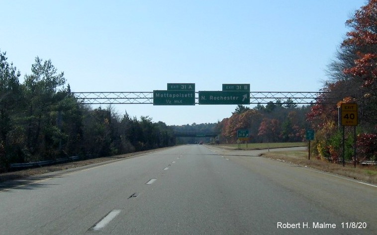 Image of overhead signage at the ramp to the North Rochester exit with new milepost based exit numbers and new numbered gore sign with yellow old exit tab below on I-195 West in Mattapoisett, November 2020