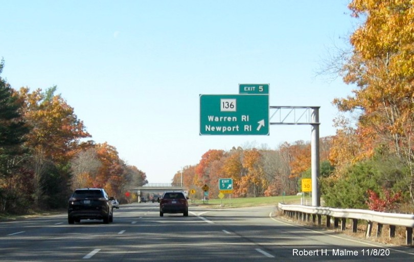Image of overhead sign at exit ramp for MA 136 with new milepost based exit number and renumbered gore sign with new yellow old exit number tab below on I-195 West in Swansea, November 2020