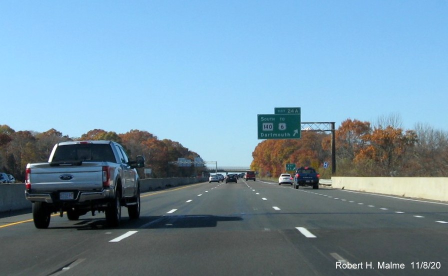 Image of overhead ramp sign for MA 140 South exit with new milepost based exit number and renumbered gore sign with yellow old exit number tab below on I-195 West in New Bedford, November 2020