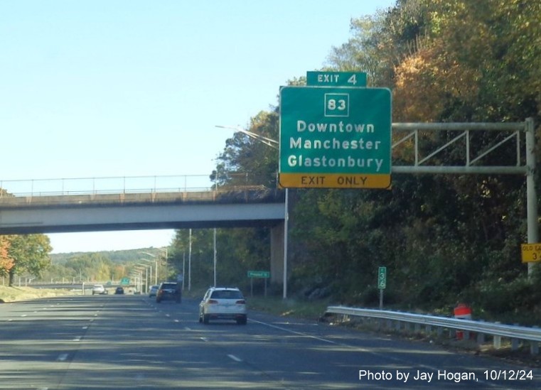 Image of 1 mile advance overhead sign for CT 83 exit with new milepost based exit number 
      and yellow Old Exit 3 sign on support post, by Jay Hogan, October 2024