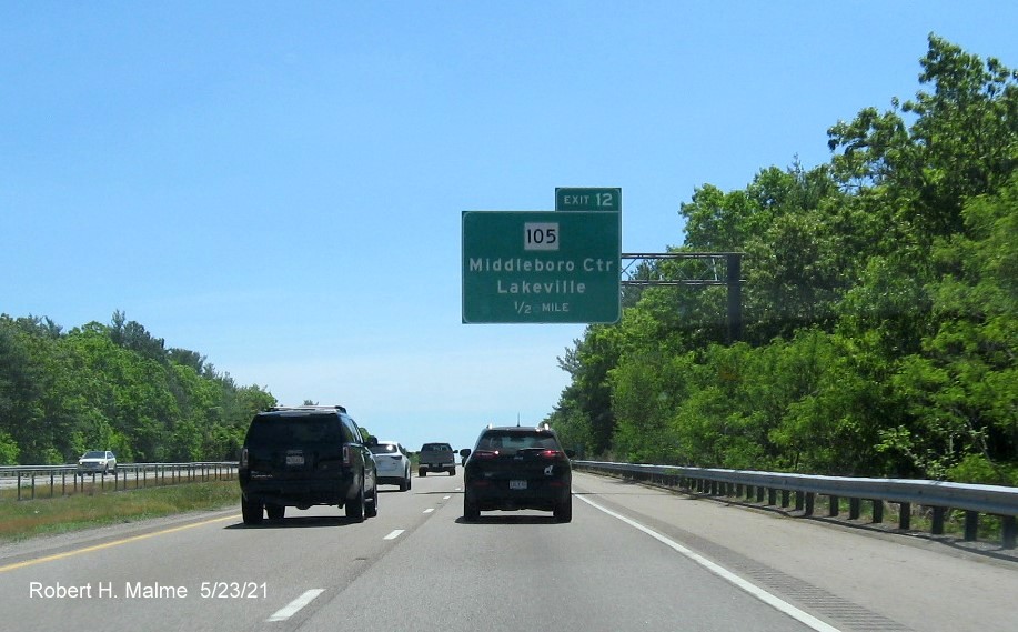 Image of 1/2 mile advance sign for MA 105 exit with new milepost based exit number and yellow Old Exit 4 advisory sign hidden by trees on support on I-495 South in Middleboro, May 2021