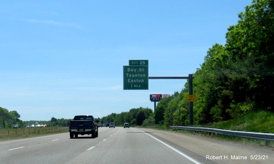 Image of 1 mile advance overhead sign for Bay Street exit with new milepost based exit number and yellow Old Exit 9 advisory sign on support on I-495 South in Taunton, May 2021