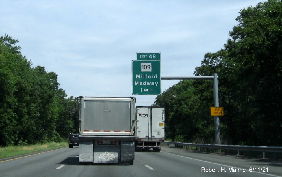 Image of 1 mile advance overhead sign for MA 109 exit with new milepost based exit number and yellow Old Exit 19 advisory sign on support on I-495 North in Milford, June 2021