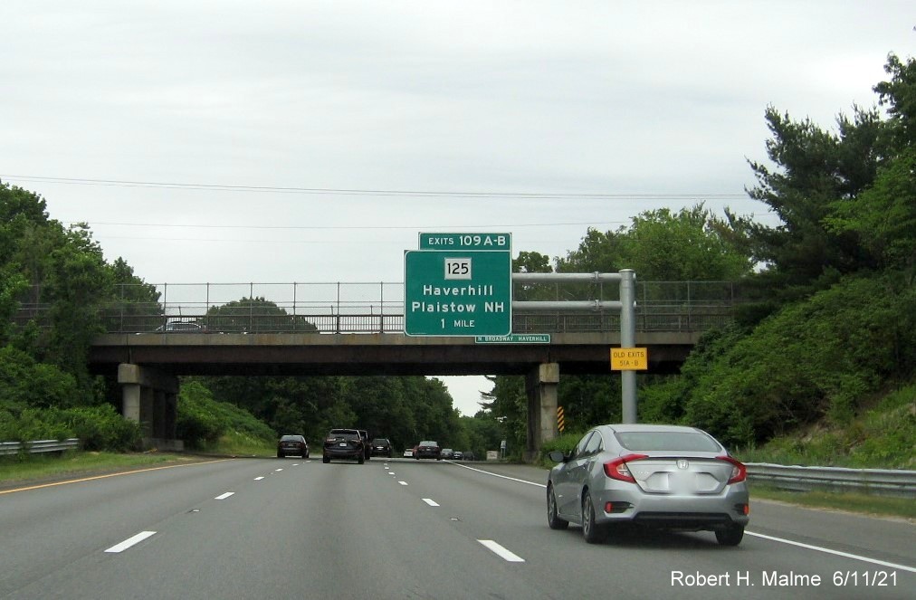 Image of 1 Mile overhead sign for MA 125 exits with new milepost based exit numbers and yellow Old Exits 51 A-B advisory sign on support on I-495 North in Haverhill, June 2021