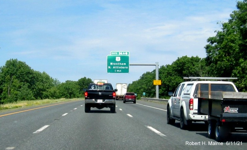 Image of 1 Mile advance overhead sign for US 1 exits with new milepost based exit numbers and yellow Old Exits 14 A-B advisory sign on support on I-495 North in Wrentham, June 2021