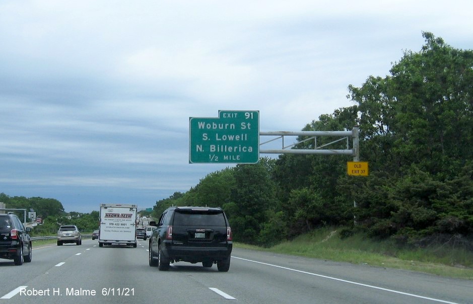 Image of 1/2 mile advance overhead sign for Woburn Street exit with new milepost based exit number and yellow Old Exit 37 advisory sign on support on I-495 North in Chelmsford, June 2021