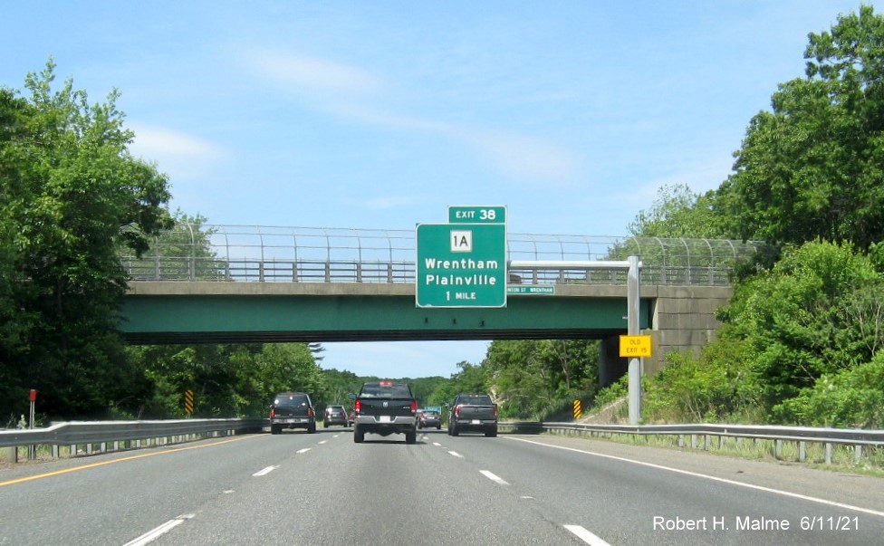 Image of 1 mile advance overhead sign for MA 1A exit with new milepost based exit number and yellow Old Exit 15 advisory sign on support on I-495 North in Wrentham, June 2021