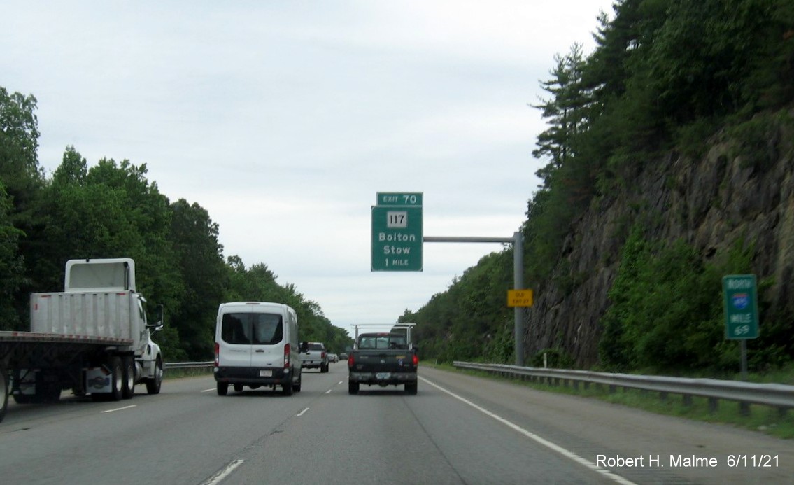 Image of 1 mile advance overhead sign for MA 117 exit with new milepost based exit number and yellow Old Exit 27 advisory sign on support on I-495 North in Bolton, June 2021
