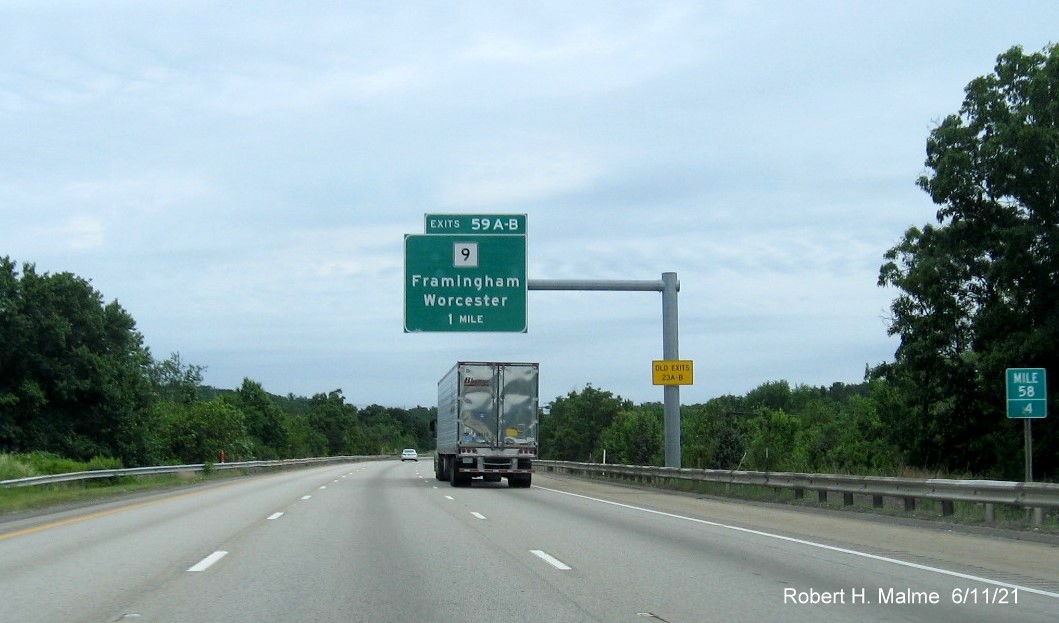 Image of 1 mile advance overhead sign for MA 9 exits with new milepost based exit numbers and yellow Old Exits 23 A-B advisory sign on support on I-495 North in Hopkinton, June 2021
